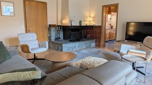 A modern living room with a fireplace, sofas, a coffee table, and a TV. - Miraflor Betty by Arosa Holiday Appartement/Fewo, Dusche und Bad, WC, 8-Bettwohn by Interhome (Arosa)