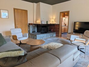 Ein modernes Wohnzimmer mit Kamin, Sofas, einem Couchtisch und einem Fernseher.
