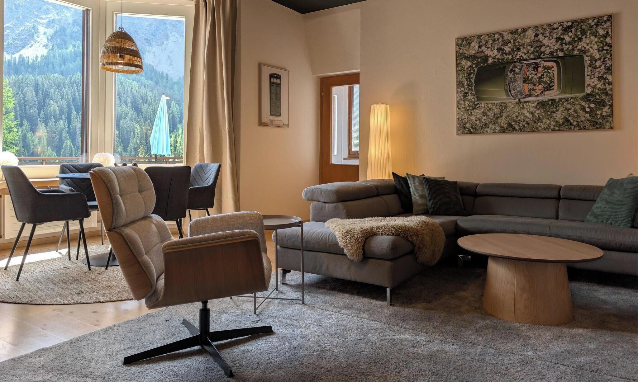 A modern living room with a sofa, chairs, a coffee table, and a dining area with a table and chairs.