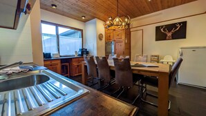 A modern kitchen with a central island, wooden ceiling, and a dining area with chairs. - Miraflor Betty by Arosa Holiday Appartement/Fewo, Dusche und Bad, WC, 8-Bettwohn by Interhome (Arosa)