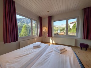 A hotel room with two beds, large windows, a floor lamp, and a view of mountains. - Miraflor Betty by Arosa Holiday Appartement/Fewo, Dusche und Bad, WC, 8-Bettwohn by Interhome (Arosa)