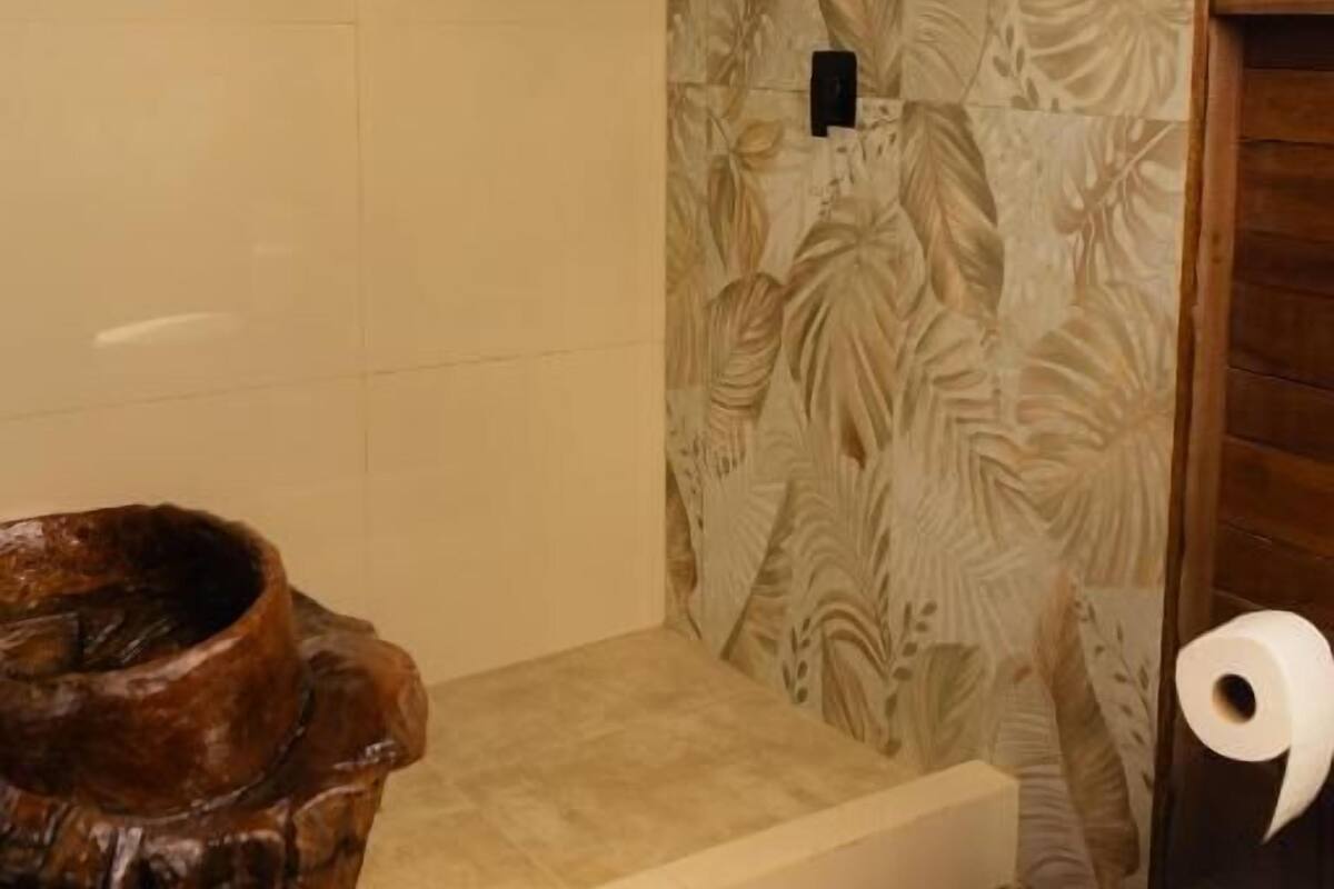 A bathroom with a shower, toilet, and a wooden basin.