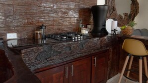 A kitchen with a stone countertop, wooden cabinets, a gas stove, and a bar stool.
