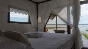 A bedroom with a bed, a window, and a view of the water.