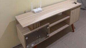 Une coiffeuse en bois avec un miroir, un petit appareil blanc posé sur le dessus et un meuble de rangement en dessous.
