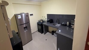 Une cuisine de taille réduite équipée d’un réfrigérateur, d’une cuisinière, d’un évier et d’un ventilateur de plafond.