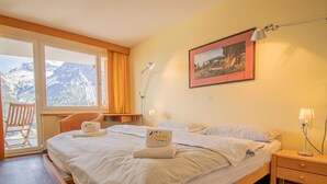 A hotel room with a large bed, a balcony with a chair, and a mountain view. - Casa Linda 8 by Arosa Holiday Appartement/Fewo,  , 7-Bettwohnung Linda 8 by Interhome (Arosa)