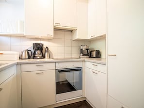 Eine Küche mit weißen Schränken, einer Kaffeemaschine, einem Wasserkocher und einem Toaster.