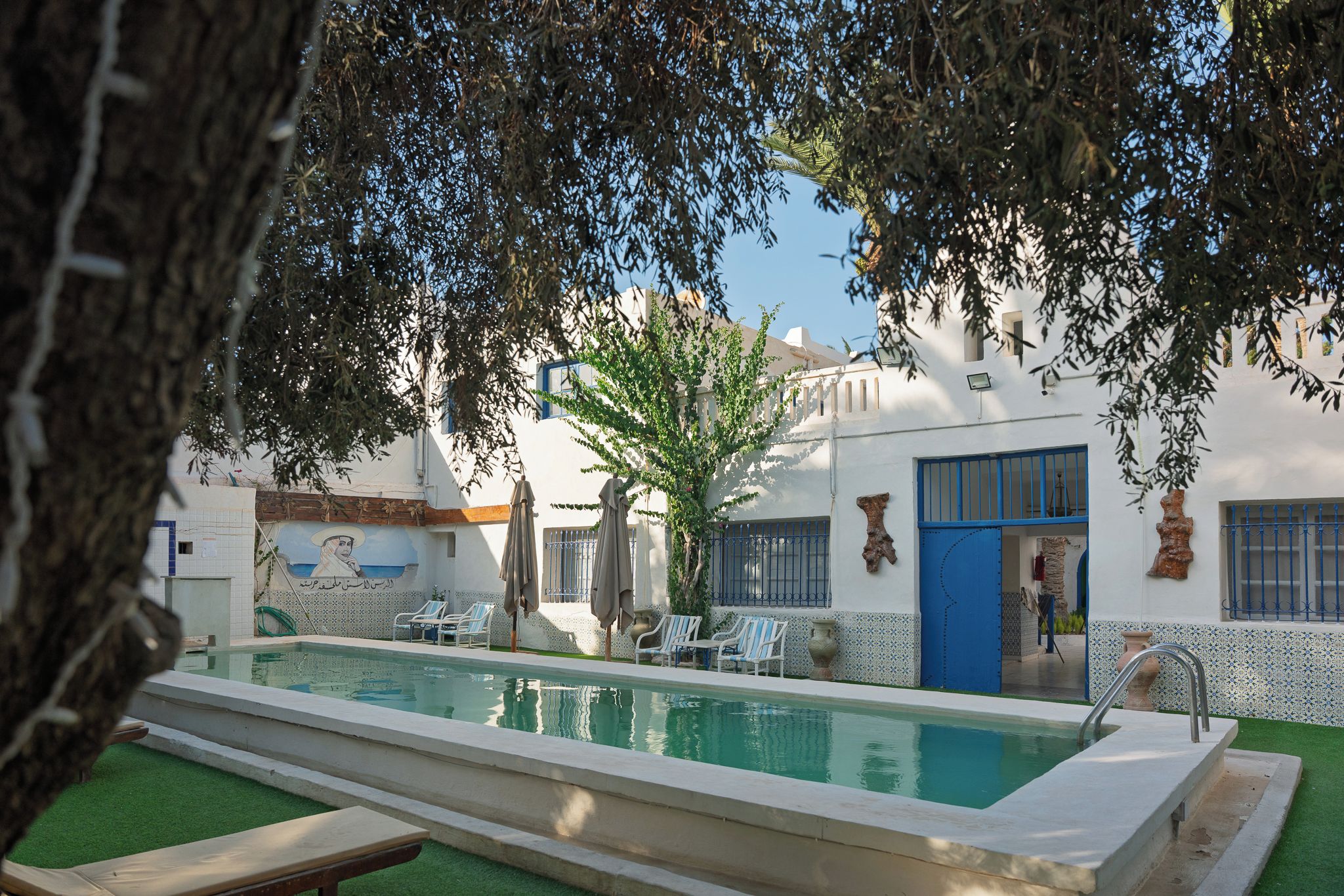 A swimming pool with lounge chairs and a tree in the foreground.