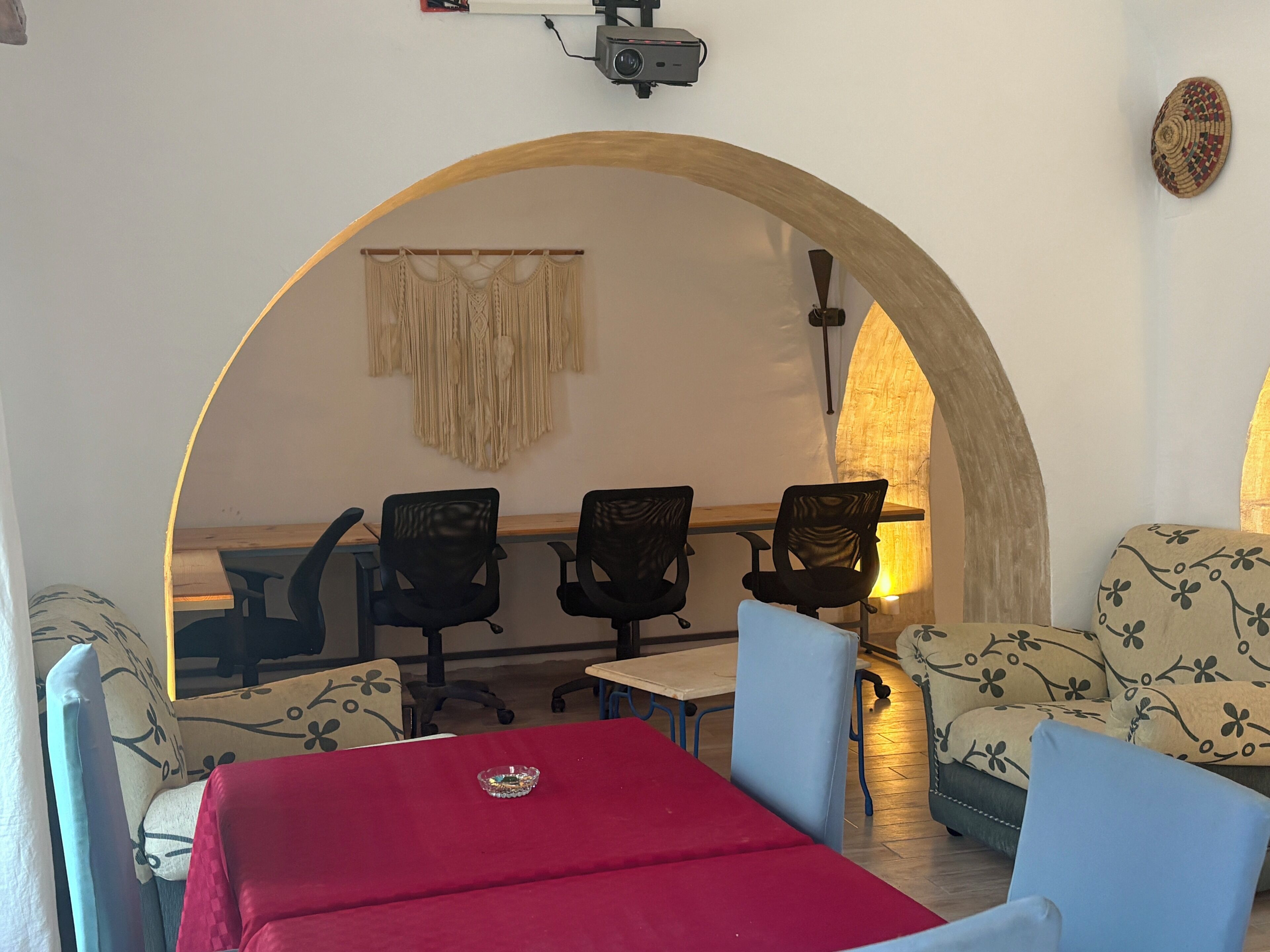 Una stanza con un arco in legno, un tavolo rosso e due sedie blu.