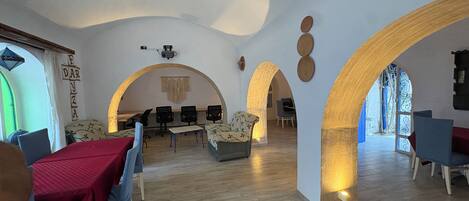 Una habitación amplia con techo alto, suelo de madera y una zona de estar con mesas y sillas.