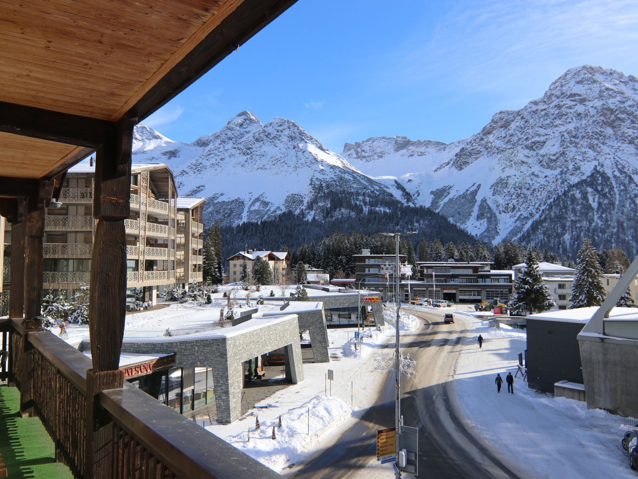 A snowy mountain town with buildings, a road, and a view of snow-covered peaks.