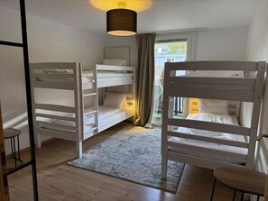 A room with bunk beds, a small table, a rug, and a hanging light fixture. - Hermann 3 by Arosa Holiday Appartement/Fewo, Dusche und Bad, WC, 8-Bettwohnung by Interhome (Arosa)