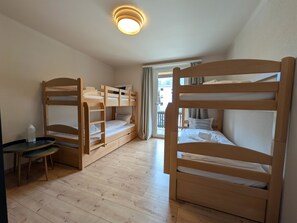 A room with bunk beds, a small table, and a ceiling light. - Hermann 2 by Arosa Holiday Appartement/Fewo, Bad, WC, 8-Bettwohnung Hermann 2 by Interhome (Arosa)