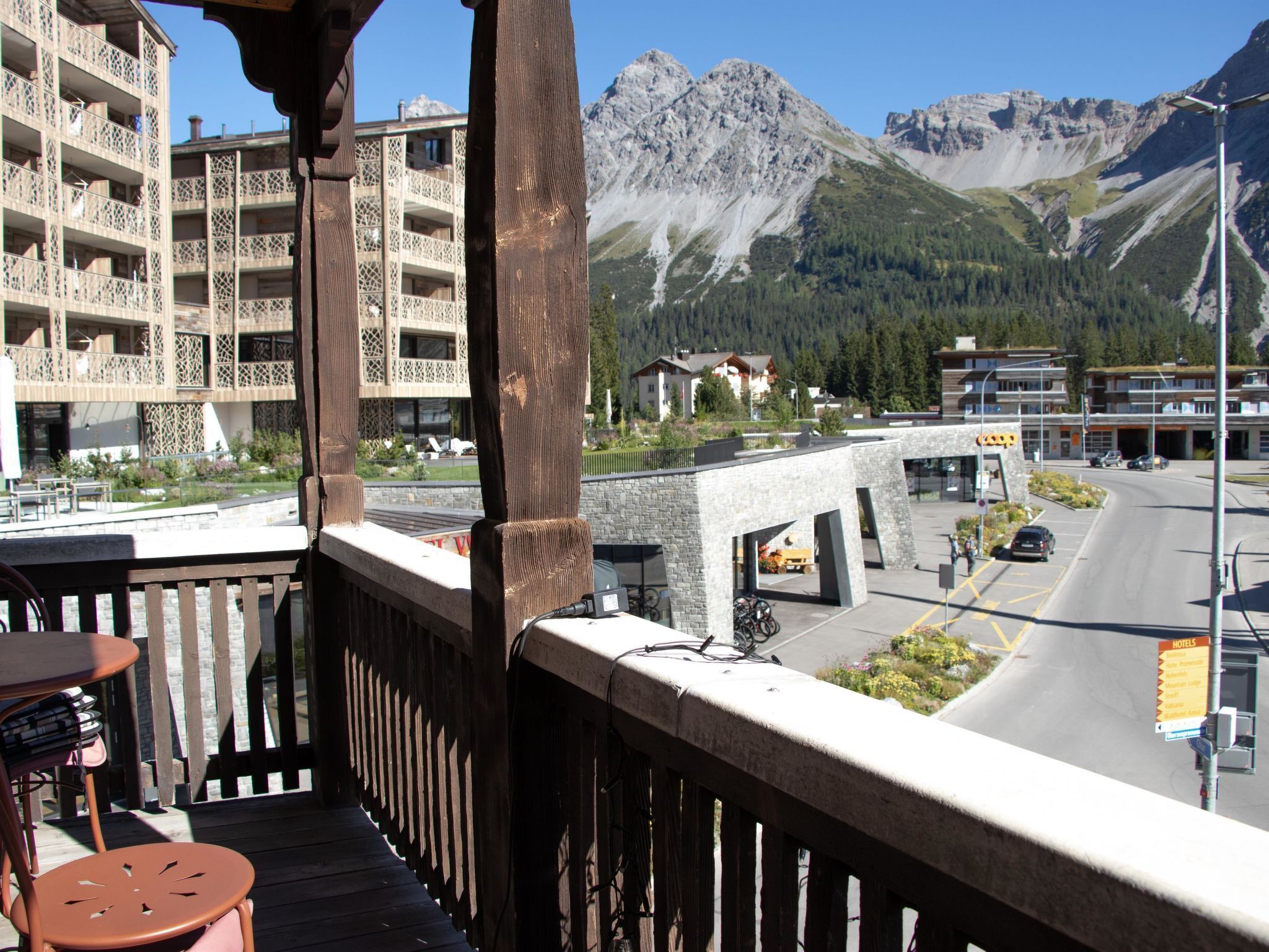 Ein Balkon mit Blick auf ein Gebirge, eine Straße mit Autos und ein Schild mit Hotelhinweisen.
