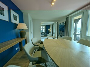 A modern hotel room with a large wooden table, two chairs, a lamp, and a view of the city through large windows. - Hermann 2 by Arosa Holiday Appartement/Fewo, Bad, WC, 8-Bettwohnung Hermann 2 by Interhome (Arosa)