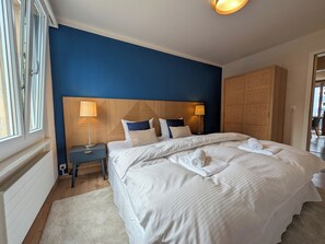 Een hotelkamer met een groot bed, nachtkastje, lamp en een houten hoofdeinde.