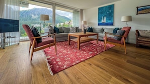 En moderne stue med sofa, stole, sofabord og fjernsyn.