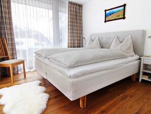 Een bed met hoofdbord, nachtkastje, stoel en een zachte, witte vloerkleed.