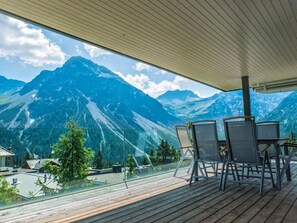 Eine Holzterrasse mit Stühlen und Blick auf eine Berglandschaft.