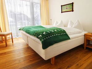 Ein Schlafzimmer mit einem Bett, einem Sessel, einem Nachttisch und einem Bild an der Wand.