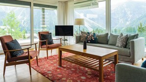 En moderne stue med et stort vindue, et fladskærms-tv og en sofa.