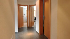 A hallway with wooden doors, a tiled floor, and a ceiling light. - Chesa Igna Appartement/Fewo, Bad, WC, 4-Bettwohnung by Interhome (Arosa)