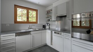 A modern kitchen with white cabinets, stainless steel appliances, a window with a view of greenery, and a dishwasher. - Chesa Igna Appartement/Fewo, Bad, WC, 4-Bettwohnung by Interhome (Arosa)