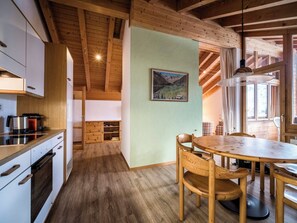 Eine gemütliche Küche mit Holzschränken, einem Esstisch mit Stühlen und einem Bild an der Wand.
