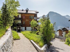 A chalet with a stone pathway leading to the entrance, surrounded by greenery and a mountain backdrop. - Tschuggenweg 14 Appartement/Fewo, Bad, WC, 5-Bettwohnung 5-Bettwohnung by Interhome (Arosa)
