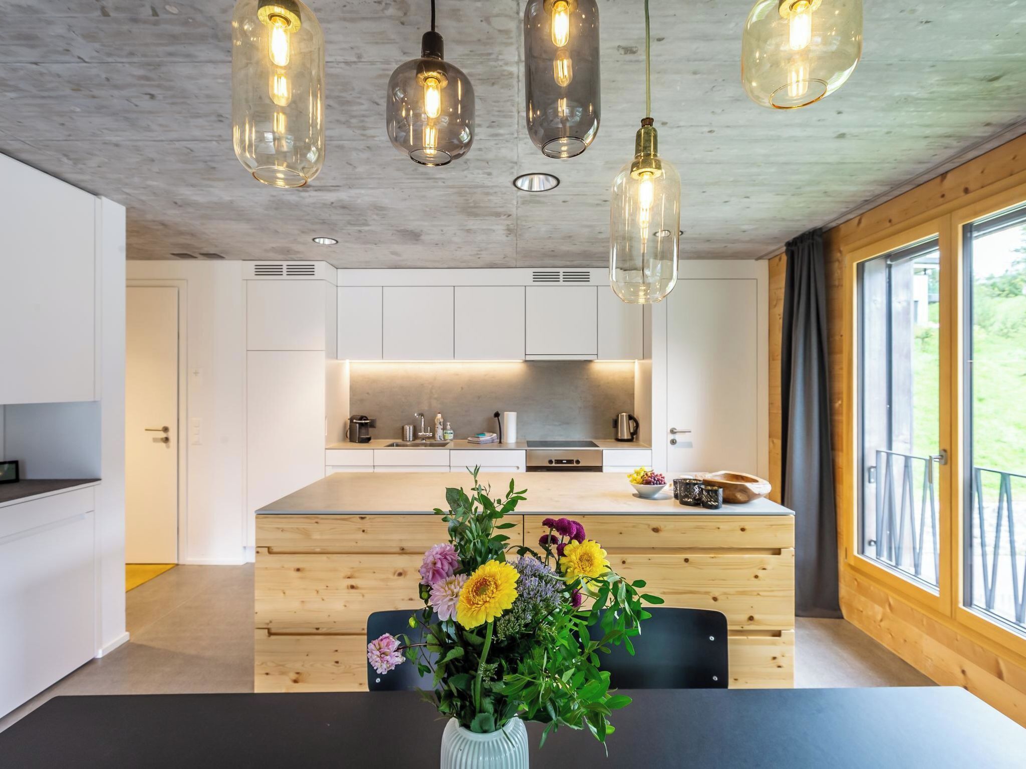 Una cocina moderna con armarios blancos, una isla central e iluminación colgante.