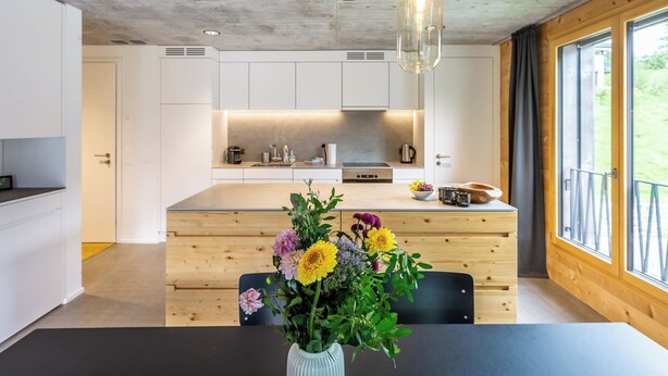 Een moderne keuken met witte kasten, een centraal eiland en hanglampen.