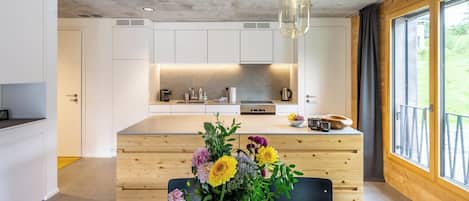 Une cuisine moderne avec des meubles blancs, un îlot central et des luminaires suspendus.