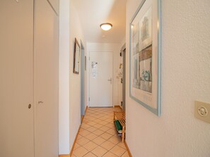 En hall med ett kaklat golv, en dörr längst in och en inramad tavla på väggen.