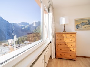 A room with a large window overlooking a mountainous landscape, a wooden dresser with drawers, and a painting on the wall. - Casa Linda 7 by Arosa Holiday Appartement/Fewo, Dusche, WC, Balkon Linda 7 by Interhome (Arosa)