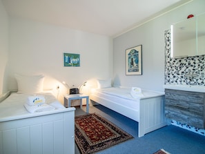 A hotel room with two beds, a small table, a nightstand, a mirror, and a patterned wall. - Casa Linda 7 by Arosa Holiday Appartement/Fewo, Dusche, WC, Balkon Linda 7 by Interhome (Arosa)