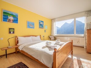 A bedroom with a wooden bed, a window with a mountain view, and artwork on the wall. - Casa Linda 7 by Arosa Holiday Appartement/Fewo, Dusche, WC, Balkon Linda 7 by Interhome (Arosa)