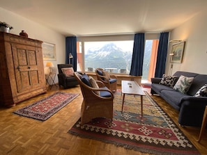 A living room with a view of mountains, a sofa, two armchairs, a coffee table, and a wooden cabinet. - Casa Linda 7 by Arosa Holiday Appartement/Fewo, Dusche, WC, Balkon Linda 7 by Interhome (Arosa)