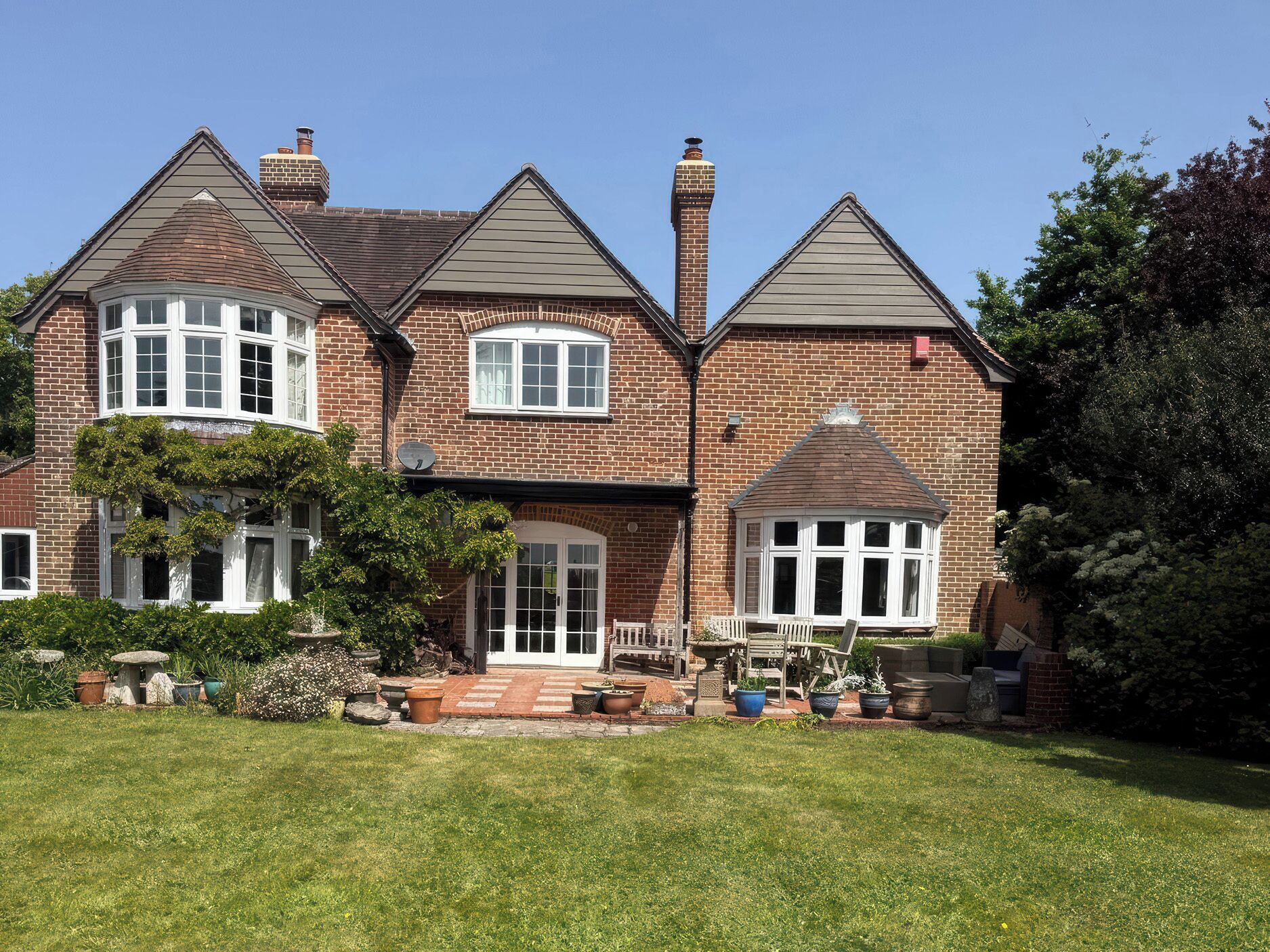 A two-story house with a brick exterior, a front porch, and a well-maintained lawn.