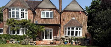 A two-story house with a brick exterior, a front porch, and a well-maintained lawn.