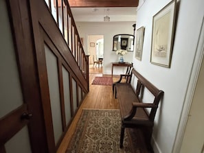 A wooden staircase leading to a dining area with a bench and a table, a rug on the floor, and framed pictures on the wall. - Avenue Road (Lymington)