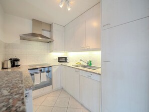 A modern kitchen with white cabinets, a stainless steel range hood, a microwave, and a dishwasher. - Casa Cresta C32 by Arosa Vacations Appartement/Fewo, Dusche und Bad, WC, 2 Schla by Interhome (Arosa)