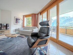 A modern living room with a leather chair, a sofa, a TV, and a balcony with a mountain view. - Casa Cresta C32 by Arosa Vacations Appartement/Fewo, Dusche und Bad, WC, 2 Schla by Interhome (Arosa)