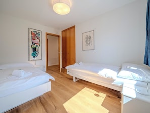 A hotel room with two single beds, a wooden floor, a door, and two framed artworks on the walls. - Casa Cresta C32 by Arosa Vacations Appartement/Fewo, Dusche und Bad, WC, 2 Schla by Interhome (Arosa)