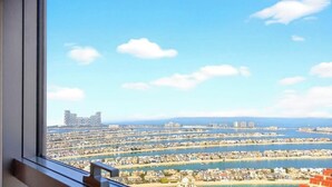 Vista panorâmica de uma cidade costeira com um porto de iates, edifícios e céu claro.