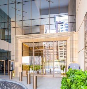 A modern building entrance with glass doors, a metal frame, and bollards. - Palm Tower Luxury Studio W Stunning Sea View (Dubai)