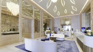 En modern hotellobby med en receptionsdisk, en sittgrupp och stora fönster.