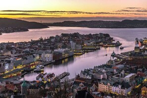 A coastal cityscape at dusk with a river, buildings, and a dock area. - Explore Bergen | 24/7 Self check-in | 500m Torget (Bergen)