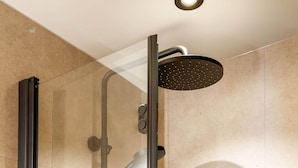 Eine Duschkabine mit Handbrause und am Wand montiertem Wasserhahn.