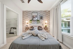 Une chambre avec un mur en briques, un lit avec une serviette, des lampes de chevet et une fenêtre avec des stores.